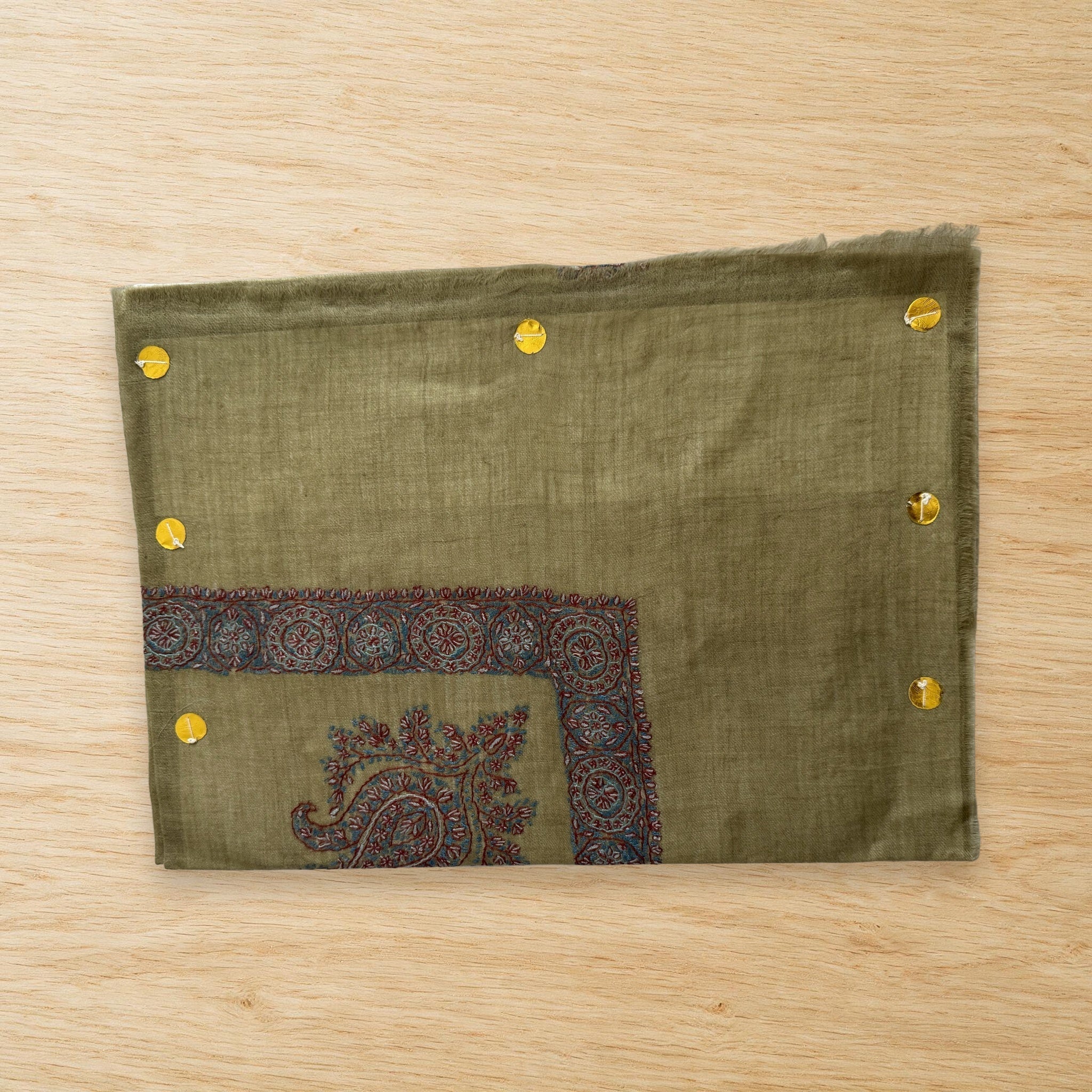 Jannah olive green Kashmiri pashmina ghutra laid flat on a wooden table, true to life colour