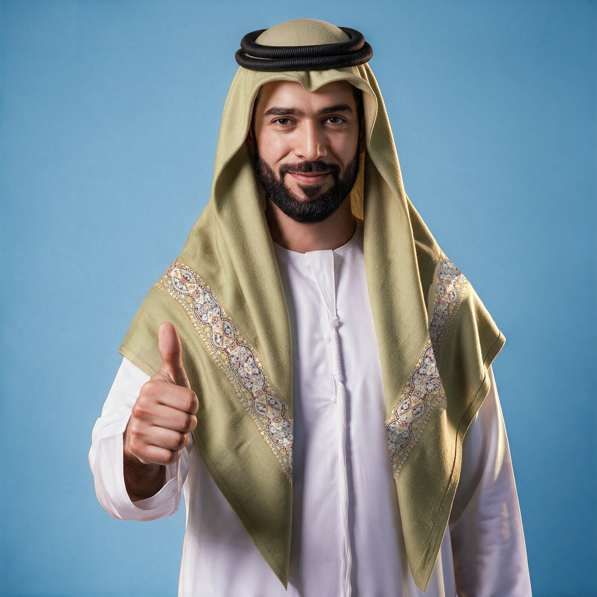 Man wearing the Bustan Kashmiri pashmina ghutra in olive with a black agal and white thobe, cream, slate blue and red sozni border on each front end