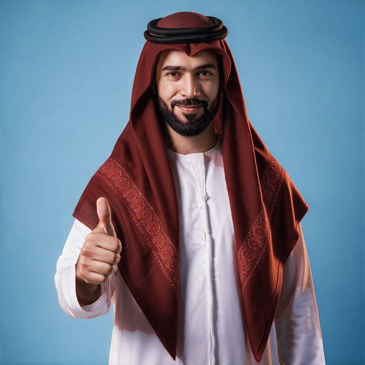 Another man wearing the Barquq Kashmiri pashmina ghutra in burgundy with a black agal and white thobe, copper rose sozni border on each front end