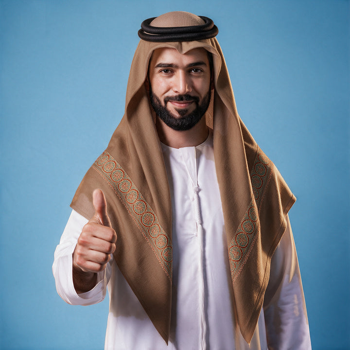Another man wearing the Nawwar Kashmiri pashmina ghutra in dusty rose with a black agal and white thobe, rust orange and teal sozni border on each front end