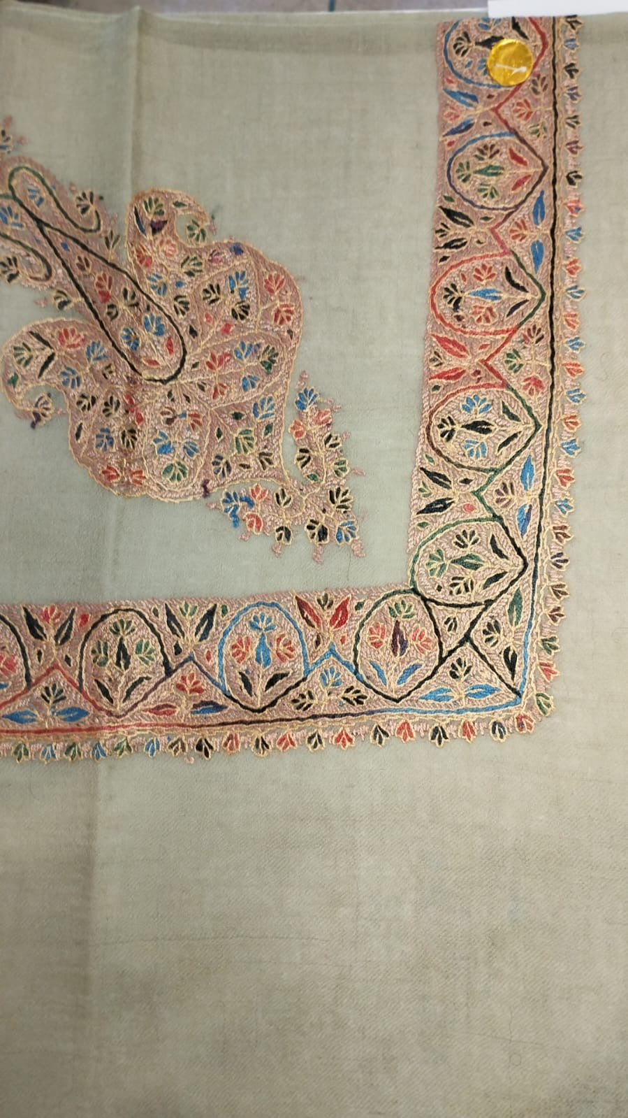 Qantara Kashmiri pashmina ghutra, oatmeal base with a peach and black corner motif and an arched border, touched with sky blue and coral