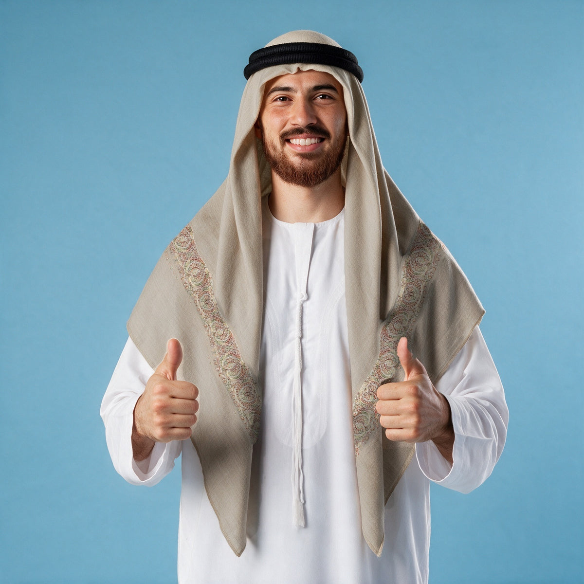 Man wearing the Busad Qalam Kaari Super Turma Kashmiri semi pashmina in light greige with a black agal and white thobe, delicate olive, coral, rust and cream pen-work border on each front end
