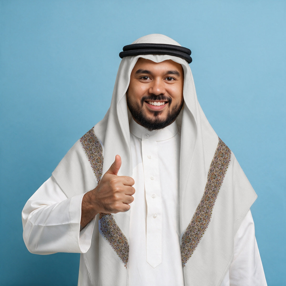 Man wearing the Ajwa Qalam Kaari Super Turma Kashmiri semi pashmina in soft natural white with a black agal and white thobe, dense dark brown, pastel pink, blue and gold multicolour pen-work border on each front end