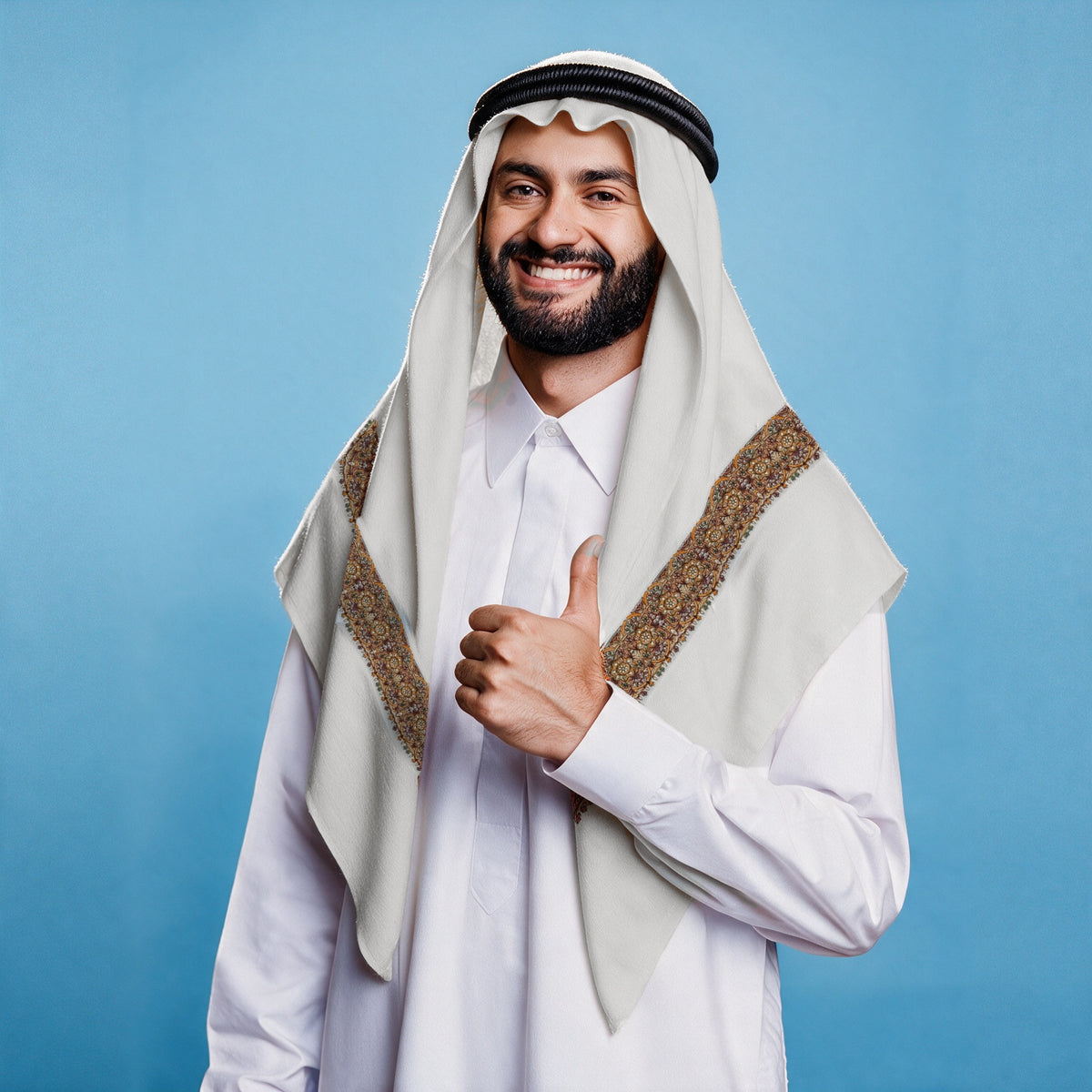 Man wearing the Kahraba Qalam Kaari Super Turma Kashmiri semi pashmina in soft natural white with a black agal and white thobe, dense amber gold, copper and maroon pen-work border on each front end