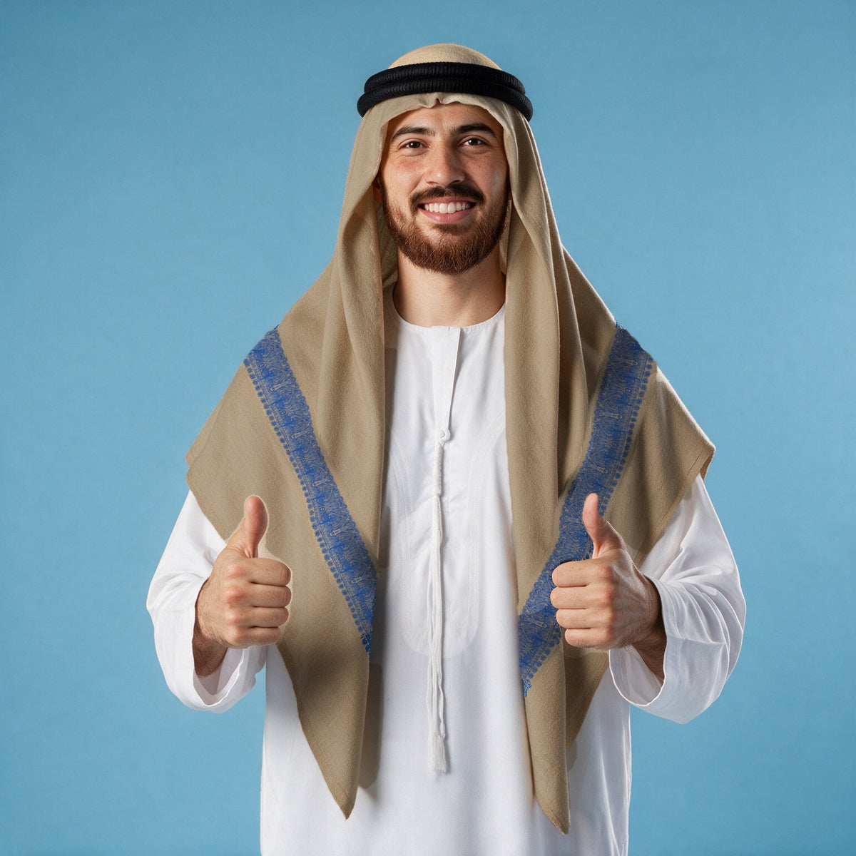 Man wearing the Nili Qalam Kaari Super Turma Kashmiri semi pashmina in warm sand beige with a black agal and white thobe, cobalt blue pen-work border on each front end