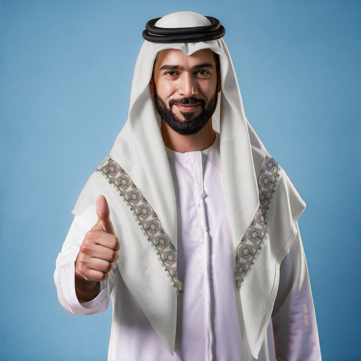 Man wearing the Mina Qalam Kaari Super Turma Kashmiri semi pashmina in soft natural white with a black agal and white thobe, pink, deep green and yellow hexagonal medallion pen-work border on each front end