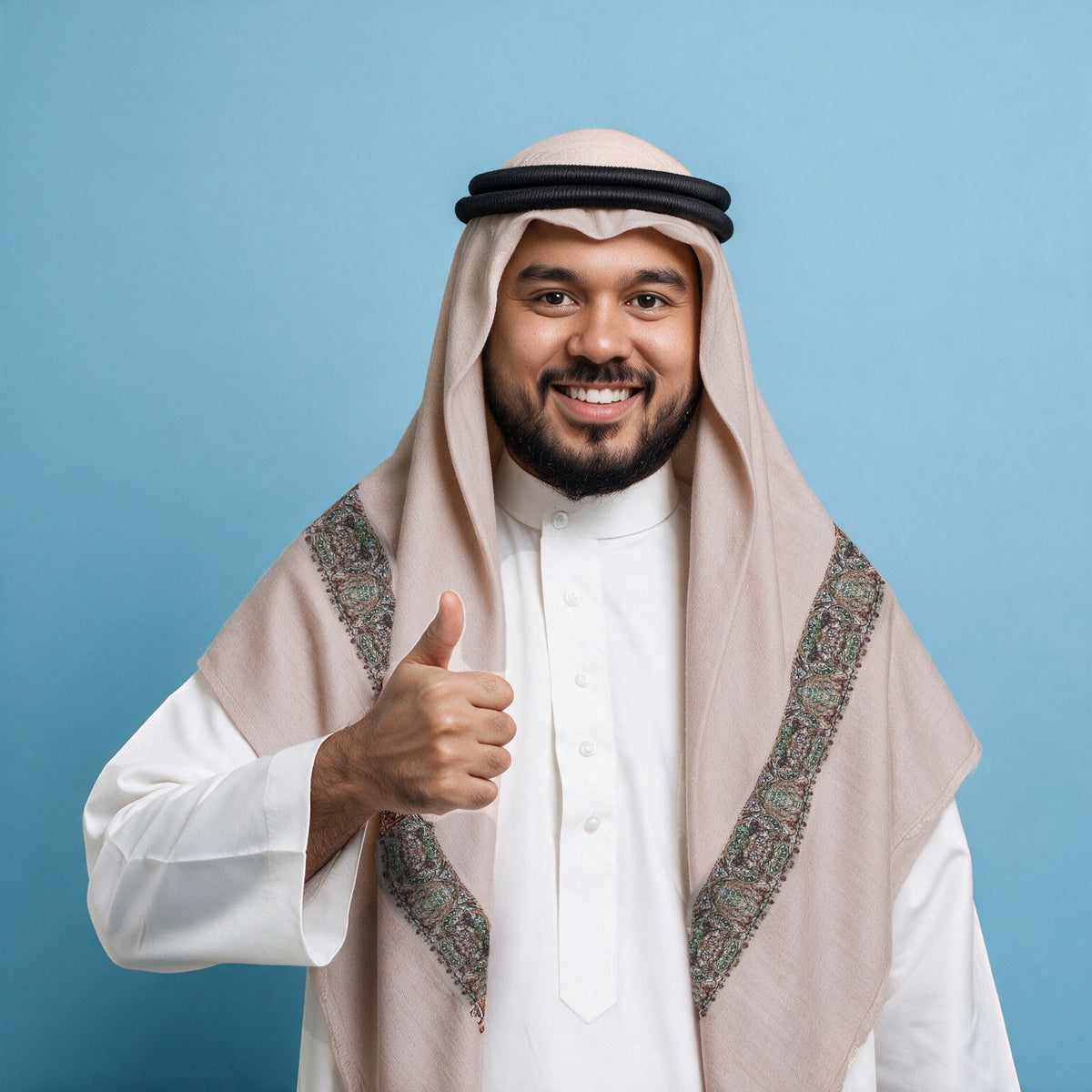 Man wearing the Atiq Qalam Kaari Super Turma Kashmiri semi pashmina in pale blush ivory with a black agal and white thobe, dense olive green, rust, white and brown multicolour pen-work border on each front end