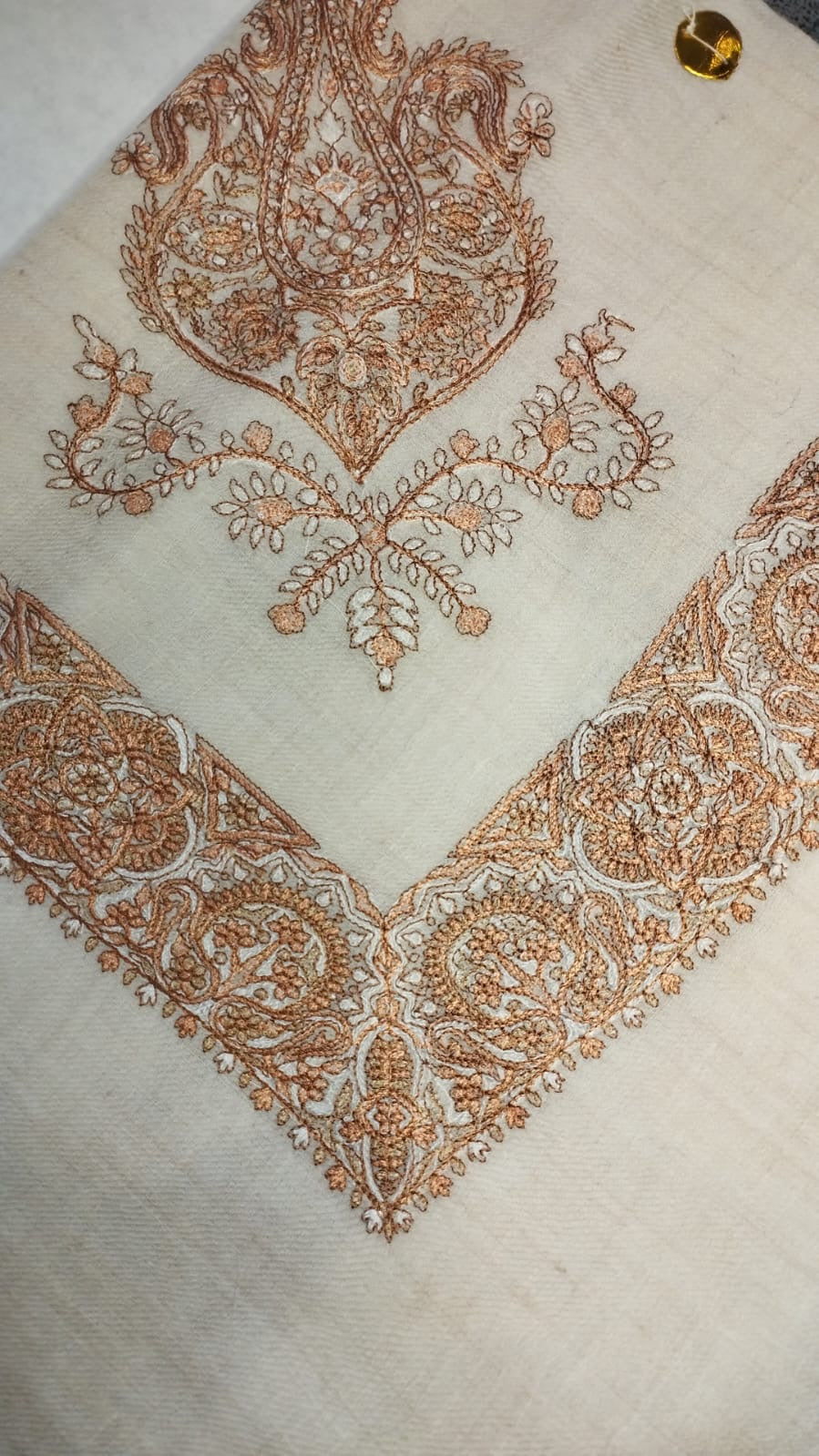 Surur Qalam Kaari Pashmina folded to a point at the corner, showing the copper and ivory paisley motif and rosette border