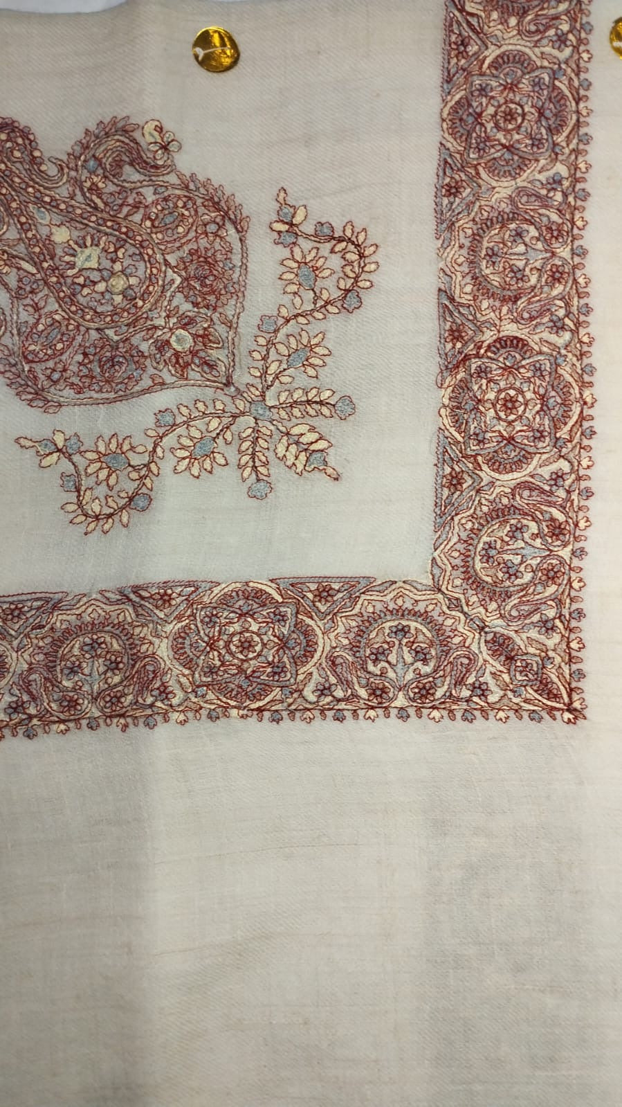 Qasida Qalam Kaari Pashmina laid flat, madder red, cream and slate blue paisley corner motif and rosette border on a natural oatmeal ground
