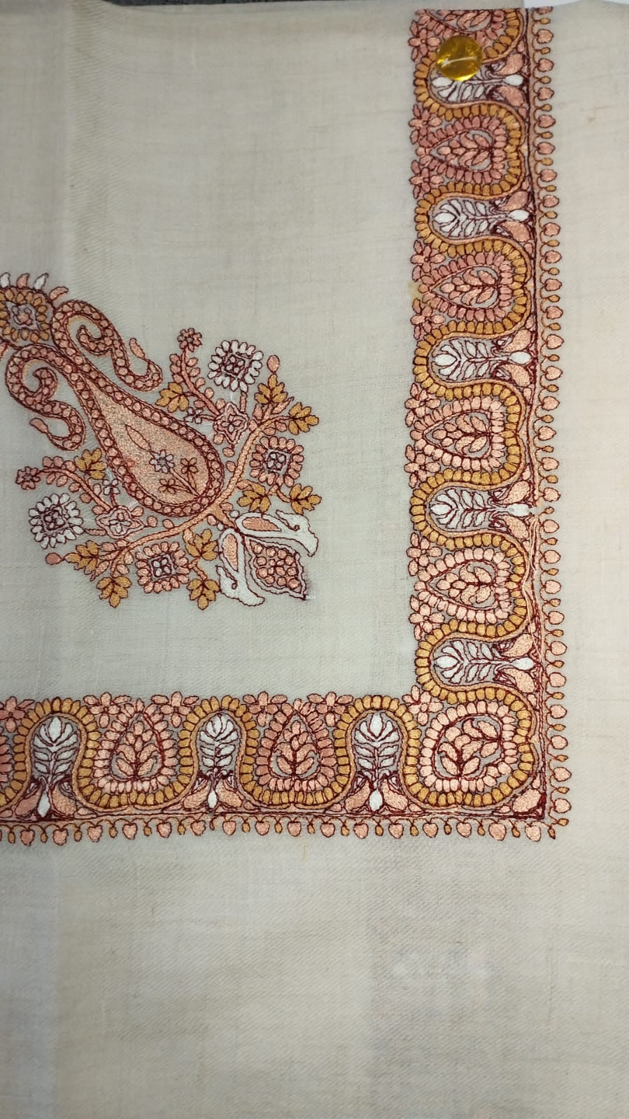 Zaffa Qalam Kaari Pashmina laid flat, salmon pink, ochre and maroon paisley corner motif and winding paisley border on a natural oatmeal ground