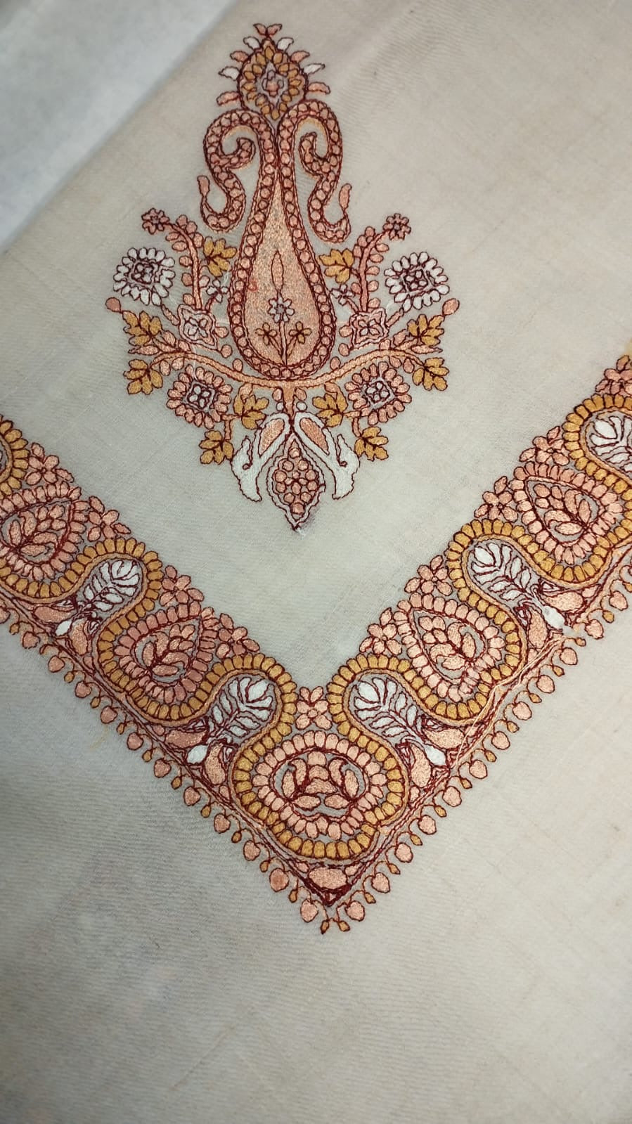 Zaffa Qalam Kaari Pashmina folded to a point at the corner, showing the salmon pink, ochre and maroon paisley motif and winding paisley border