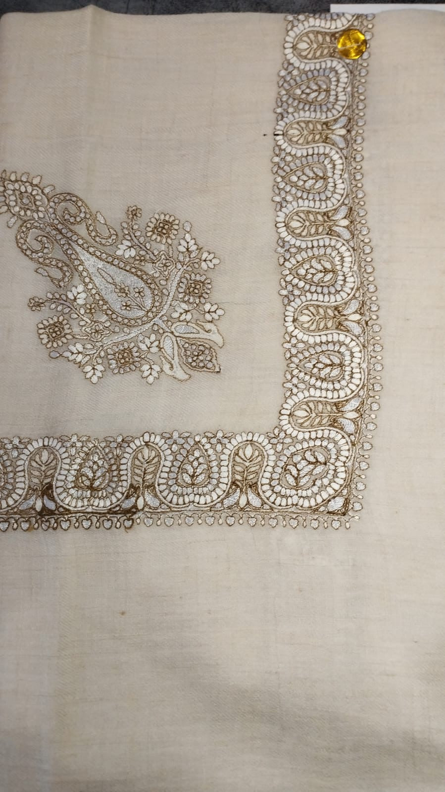Lubban Qalam Kaari Pashmina laid flat, ivory and khaki paisley corner motif and winding paisley border on a natural oatmeal ground