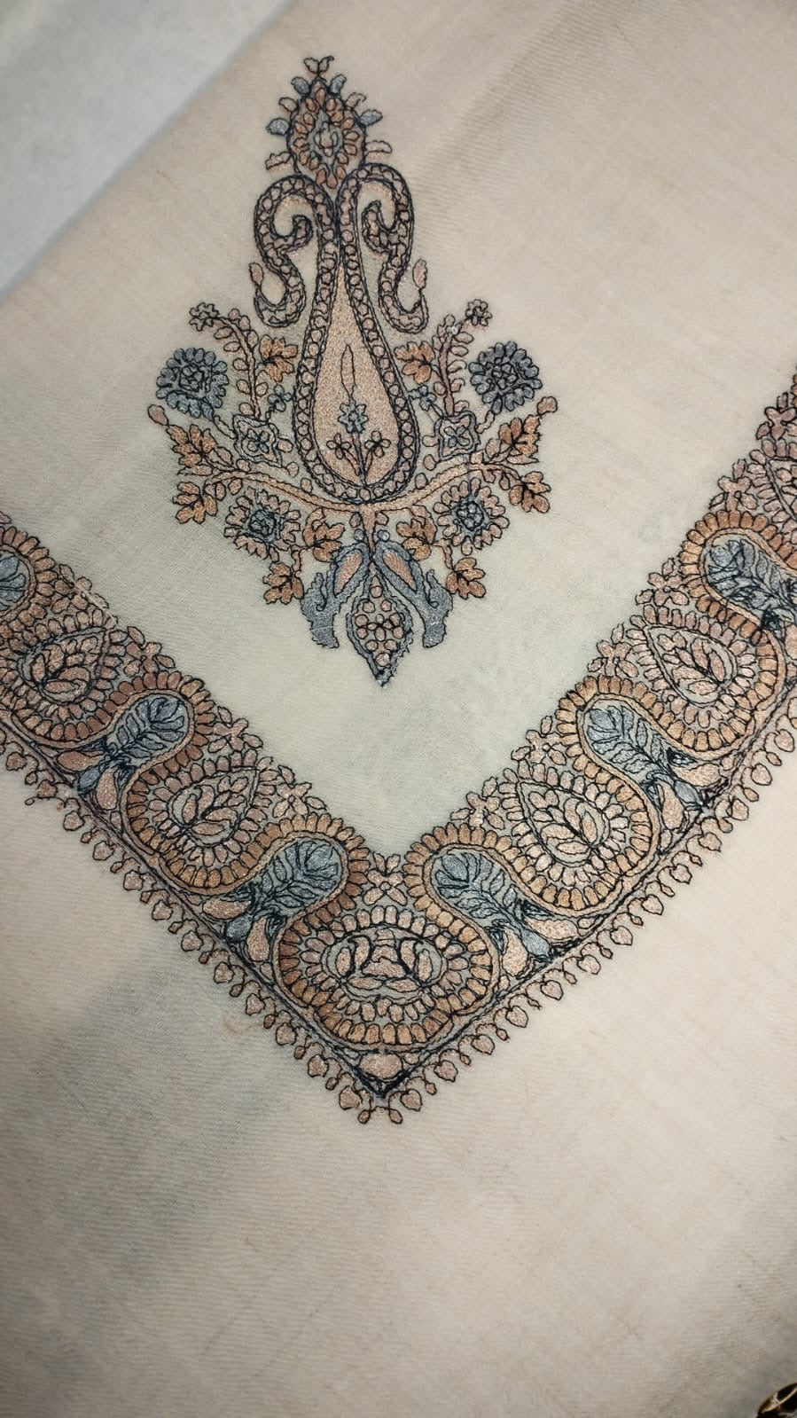 Yaraa Qalam Kaari Pashmina folded to a point at the corner, showing the apricot, charcoal and powder blue paisley motif and winding paisley border