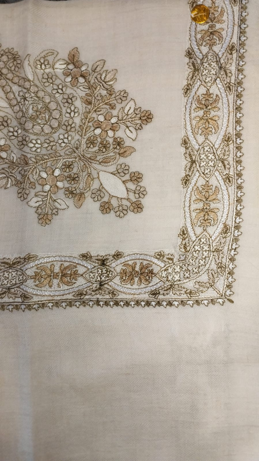 Wadi Qalam Kaari Pashmina laid flat, camel, fawn and ivory floral bouquet corner motif and interlaced ribbon border on a natural oatmeal ground