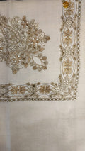 Wadi Qalam Kaari Pashmina laid flat, camel, fawn and ivory floral bouquet corner motif and interlaced ribbon border on a natural oatmeal ground