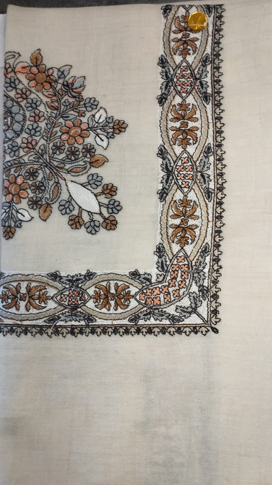 Mijmar Qalam Kaari Pashmina laid flat, burnt orange, slate and charcoal floral bouquet corner motif and interlaced ribbon border on a natural oatmeal ground