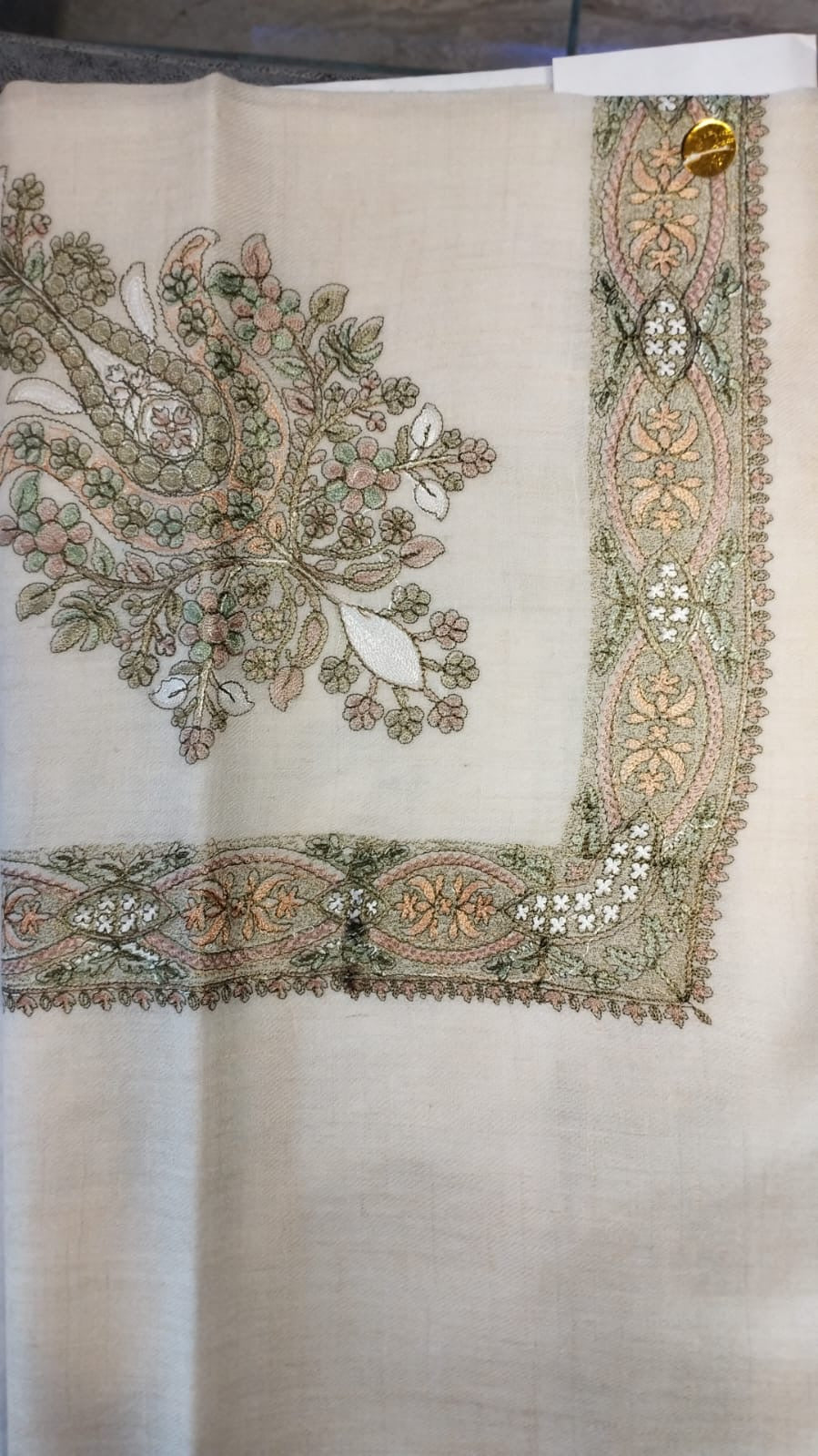 Safsaf Qalam Kaari Pashmina laid flat, sage green and peach floral bouquet corner motif and interlaced ribbon border on a natural oatmeal ground