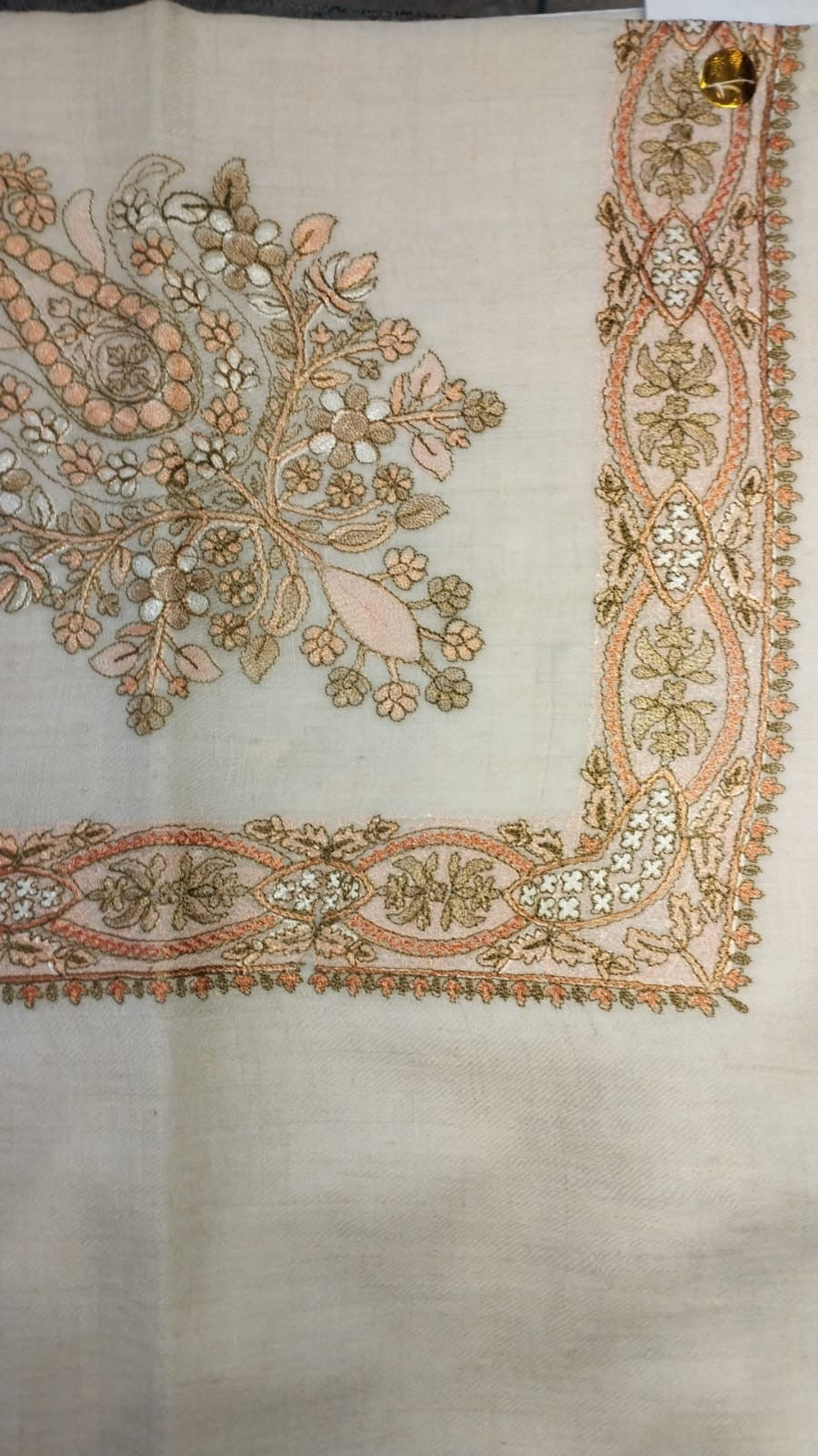 Rubai Qalam Kaari Pashmina laid flat, apricot and olive floral bouquet corner motif and interlaced ribbon border on a natural oatmeal ground