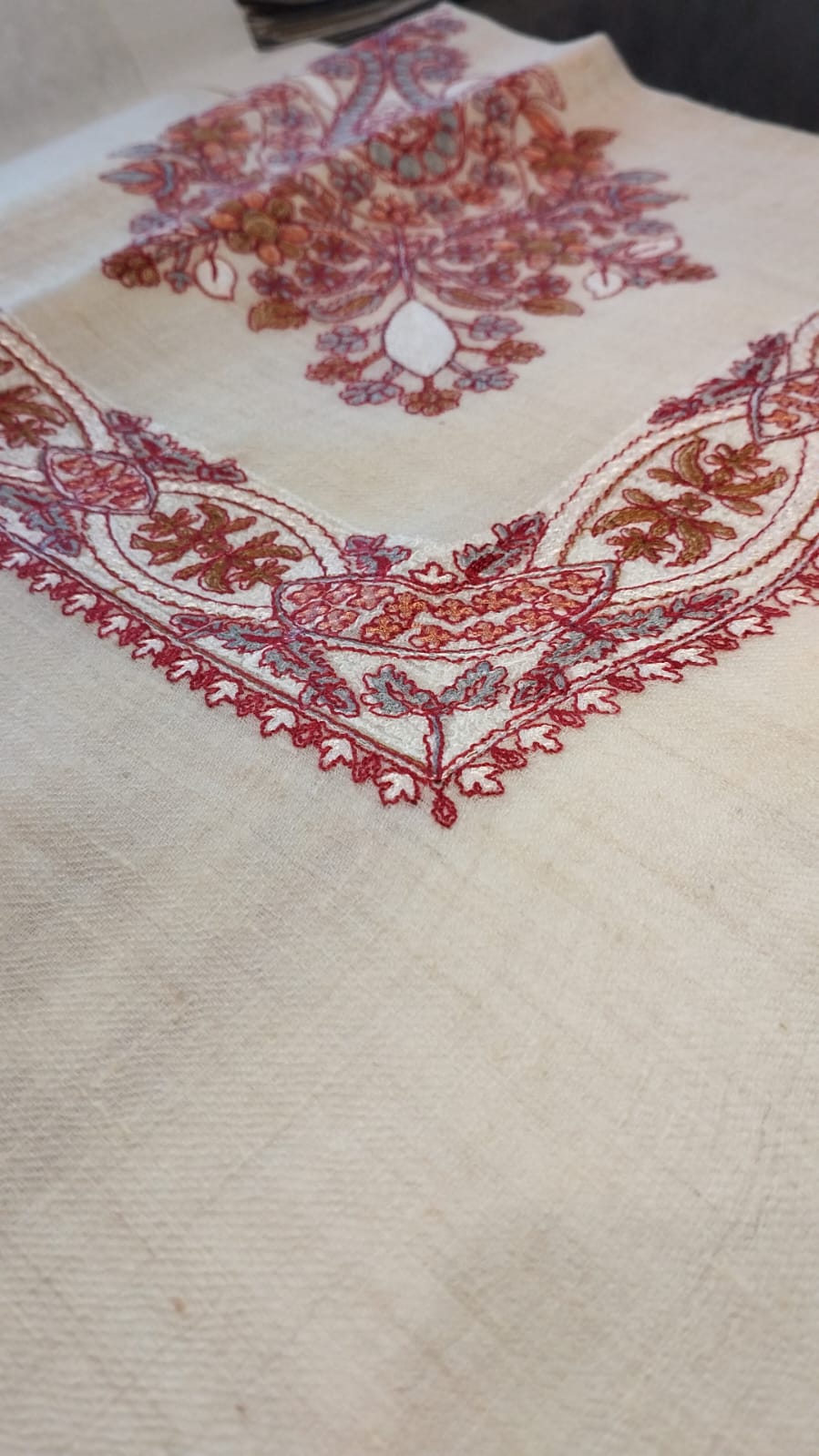 Close view of the Diwani Qalam Kaari Pashmina corner, scarlet, rust and grey-blue hand-drawn sozni