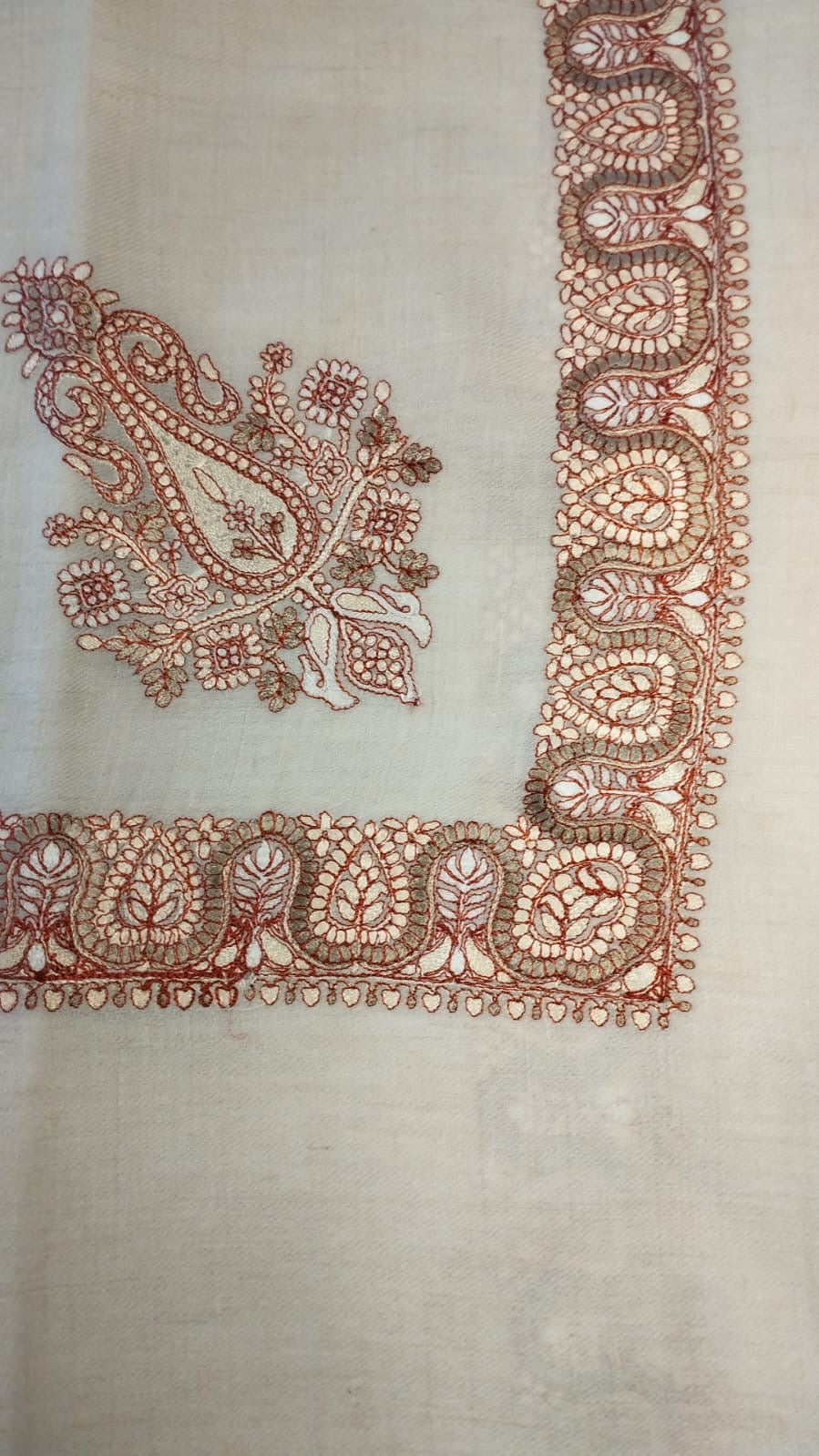 Chinar Qalam Kaari Pashmina laid flat, rust and khaki paisley corner motif and winding paisley border on a natural oatmeal ground