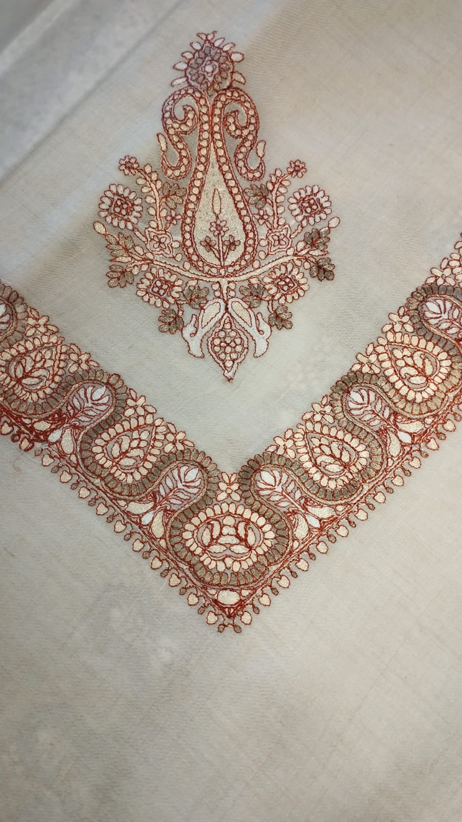 Chinar Qalam Kaari Pashmina folded to a point at the corner, showing the rust and khaki paisley motif and winding paisley border