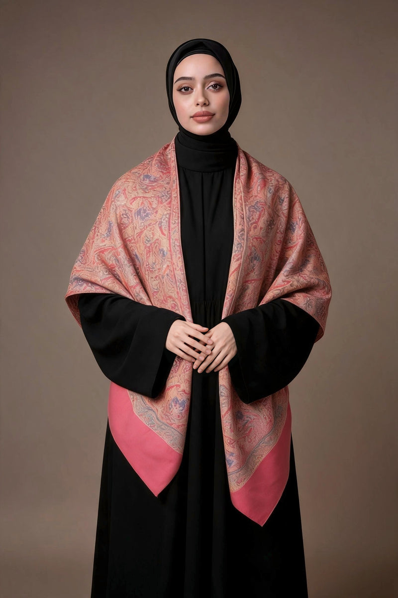 Woman in a black hijab and black abaya wearing the Jouri Kashmiri semi pashmina shawl, coral pink with rose and lilac paisley and a coral red end panel