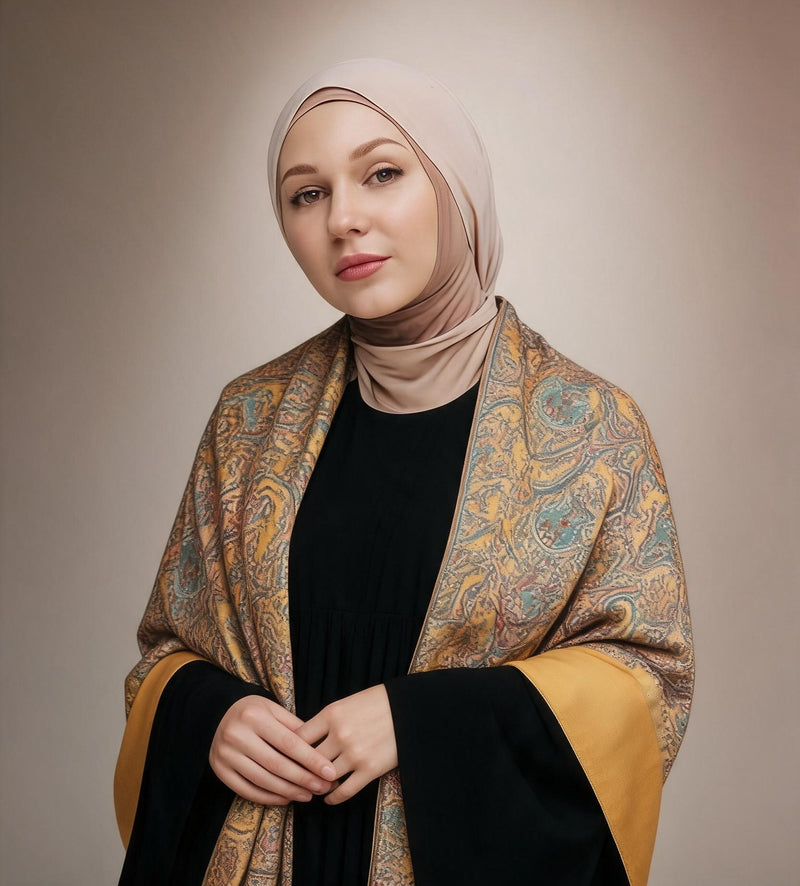 Woman in a beige hijab and black abaya wearing the Shams Kashmiri semi pashmina shawl, saffron gold with teal, rust and rose paisley